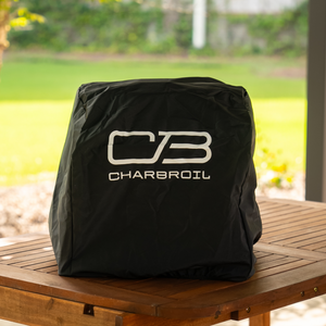 Black Char-Broil grill cover on wooden table.