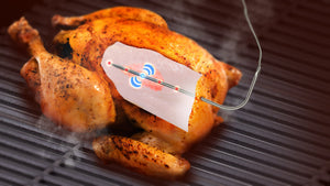 Smart thermometer probe inserted into grilled chicken for precise temperature reading.