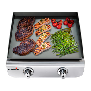Silver Char-Broil gas grill with steaks, salmon, asparagus, and tomatoes on griddle.