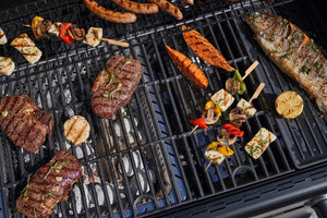 Assorted meats, fish, vegetables, and skewers grilling on a Char-Broil barbecue with visible grill marks.